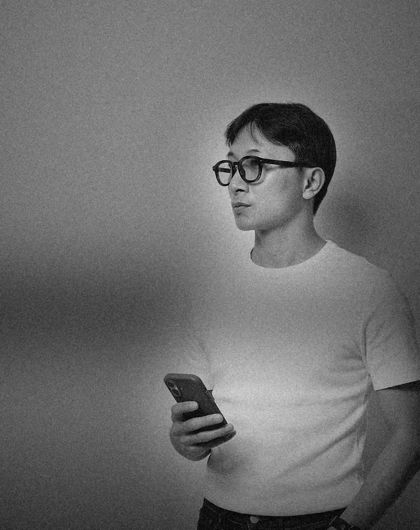 Black-and-white portrait of Nathaniel Mallo holding his phone